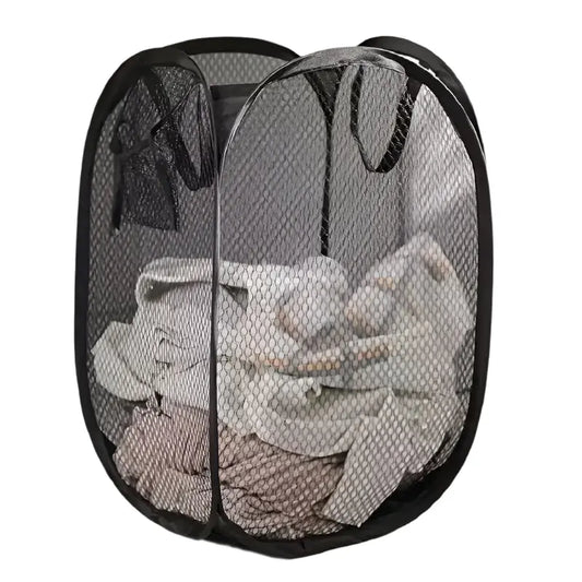Black mesh laundry basket with clothes inside on a light-colored floor.