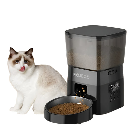 Cat sitting next to a ROJECO pet feeder on a wooden floor.