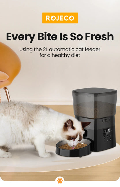 Cat eating from a ROJECO 2L automatic cat feeder on a light-colored surface.